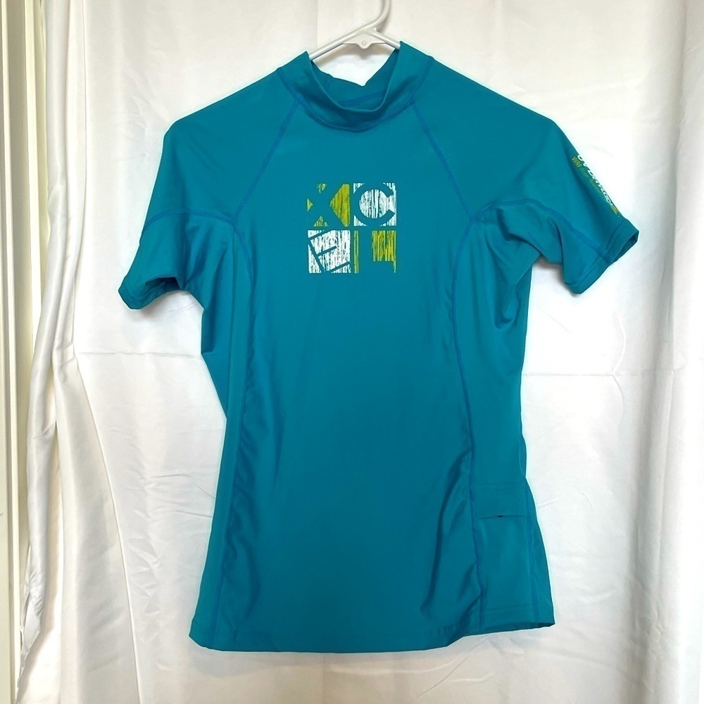 Xcel/ UV protection teal short sleeved swim shirt with one small pocket‌‌‌